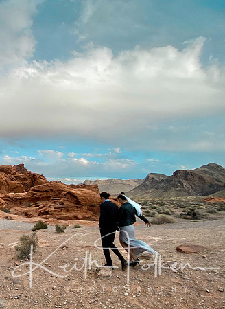 Adam and Eliska walk together with the Valley of Fire rocky background and vast sky - portrait